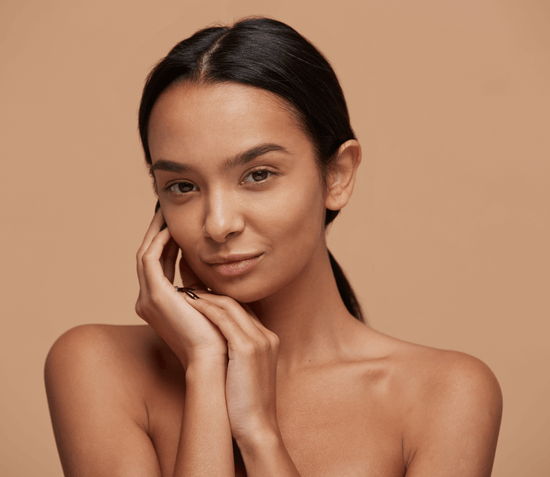 Close-up of a smiling young woman posing with her hand gently supporting her chin, radiating a natural glow.