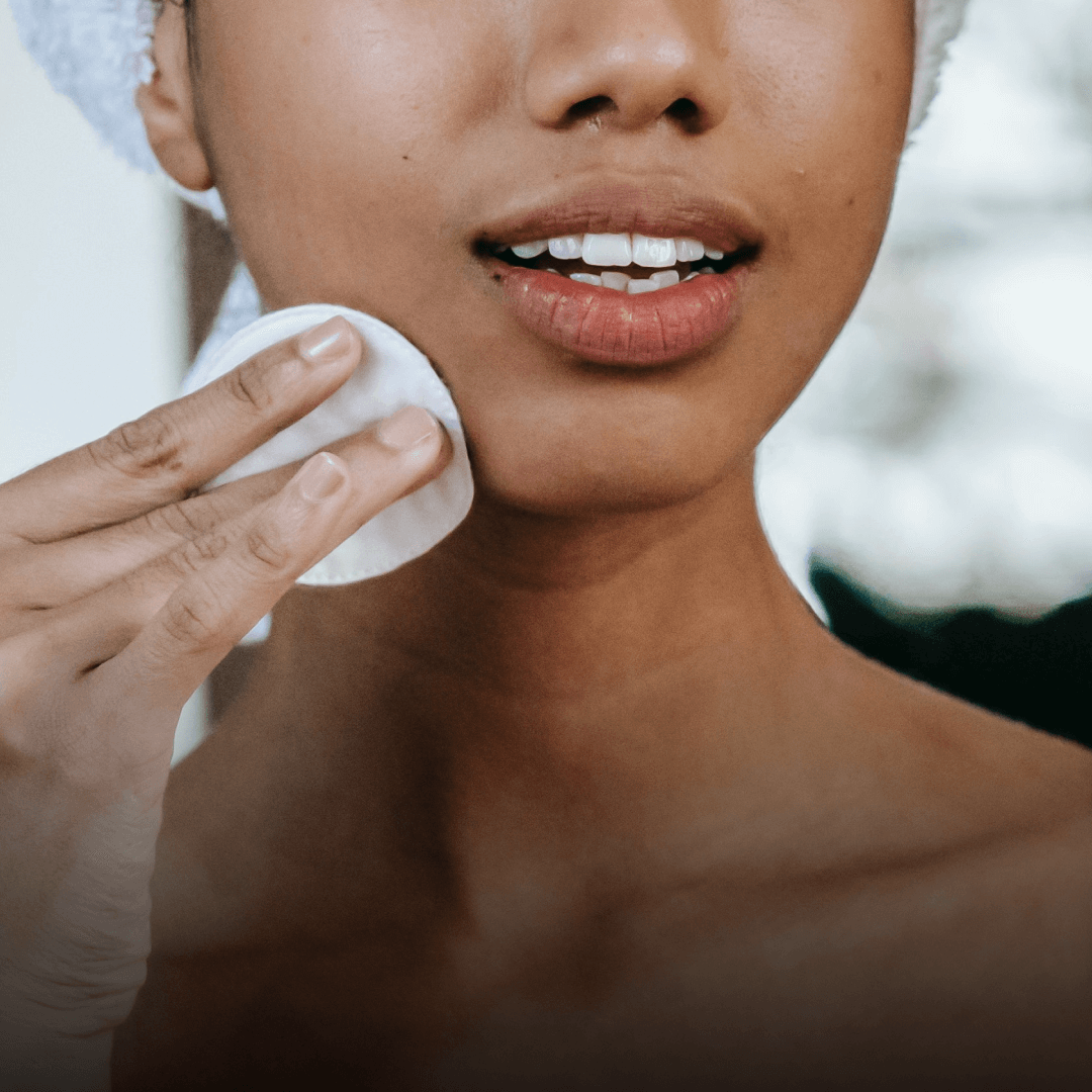 Woman using a cotton pad to cleanse her face, showcasing skincare routine and beauty care.