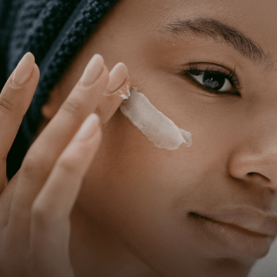 Close-up of a woman gently massaging cream into her face.