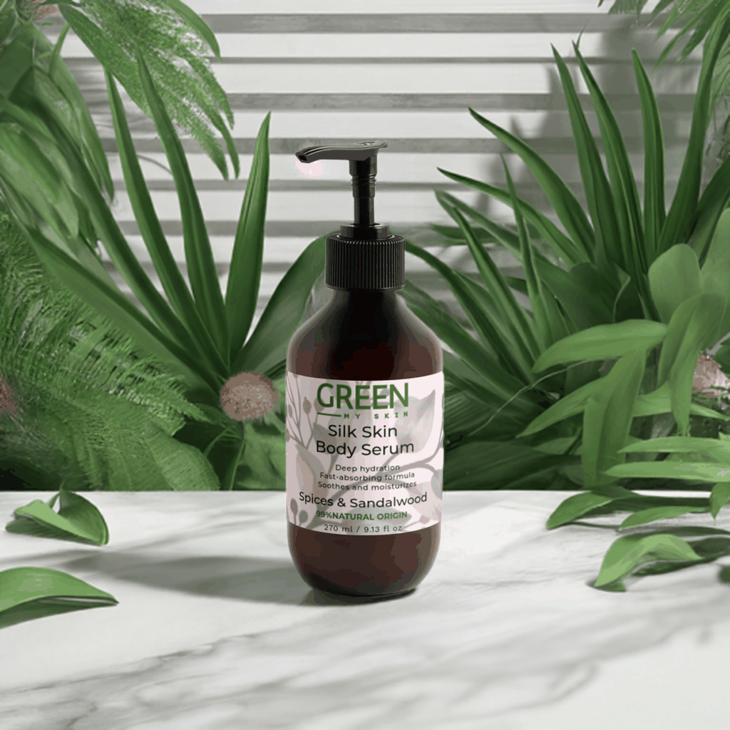 Silk-Skin-Body-Serum bottle with Spices & Sandalwood on a marble surface surrounded by green leaves.