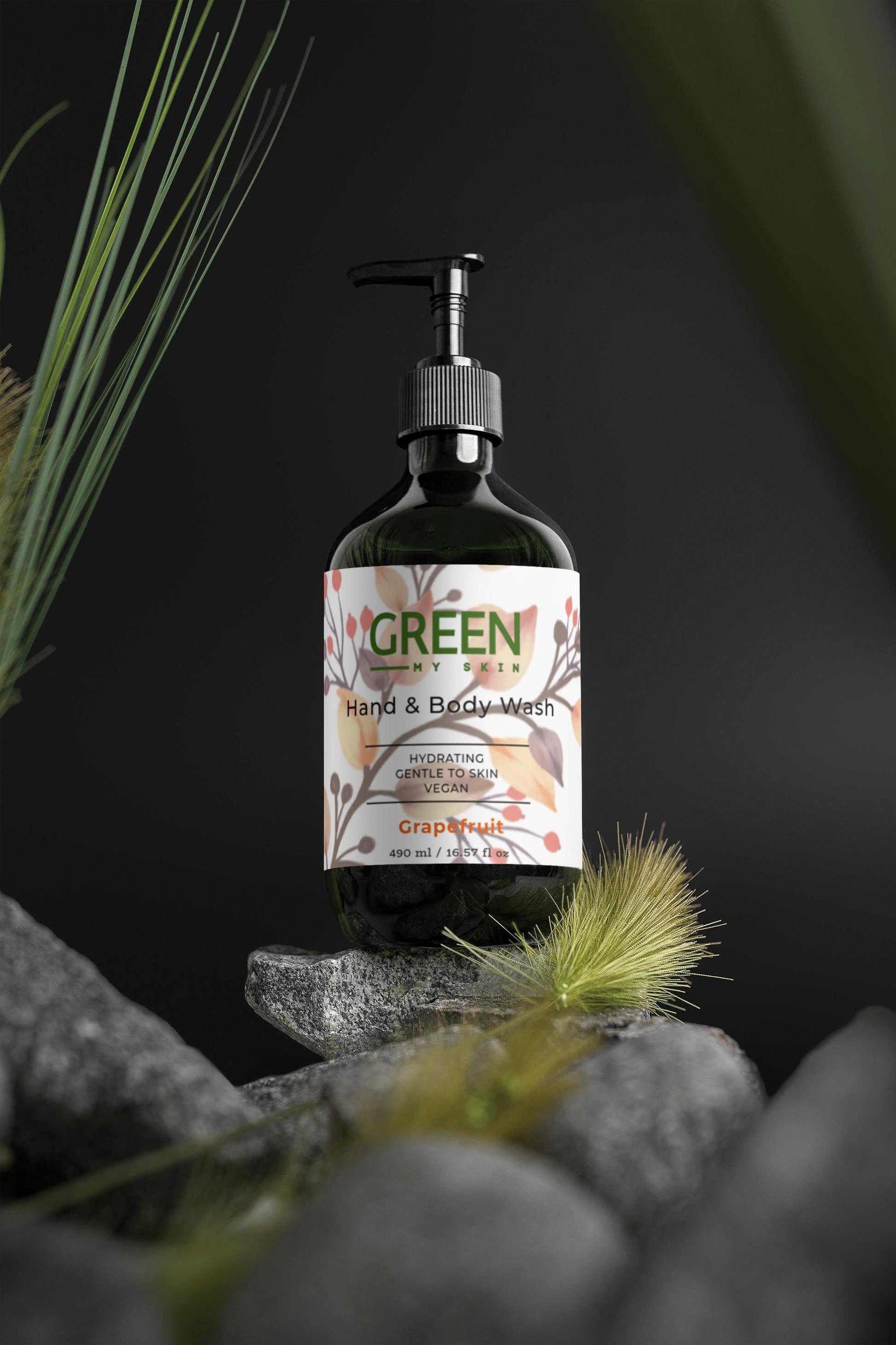Hydrating grapefruit hand-body wash bottle on rocks with greenery.