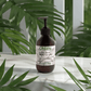 Silk-Skin-Body-Serum bottle with pump on tropical green background; features deep hydration benefits with spices and sandalwood.