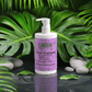Gloss-shampoo bottle with smoky green vetiver surrounded by lush green leaves and stones.