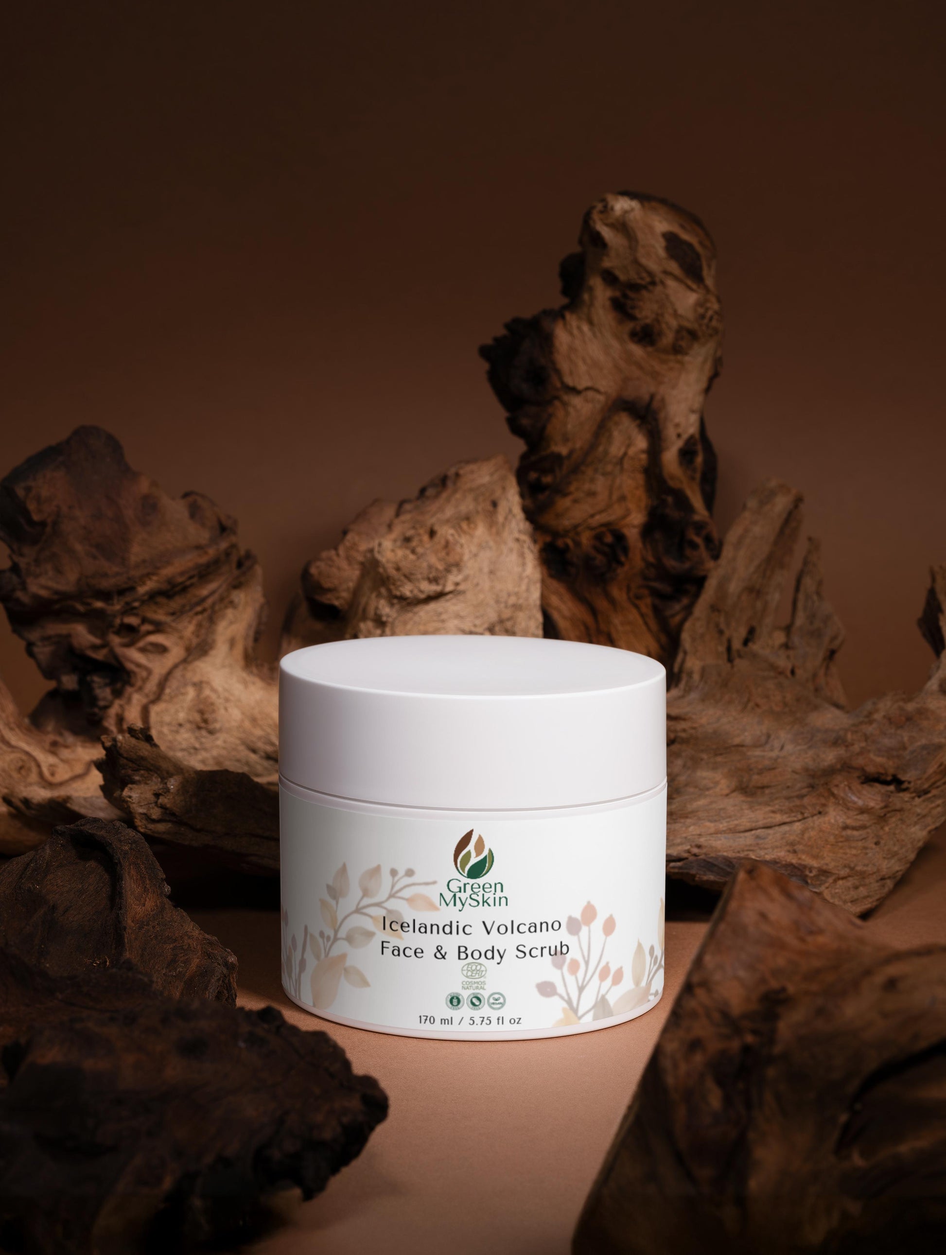 Green My Skin White jar of Icelandic Volcano Face & Body Scrub on a brown background with natural elements.